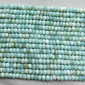 May include: A strand of light blue gemstone beads, each bead is faceted and has a slightly irregular shape. The beads are small and uniform in size.