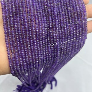 Può includere: Un filo di perle di ametista viola, sfaccettate e rotonde, con una finitura liscia e lucida. Le perle sono infilate su un filo sottile e hanno un diametro di circa 4 mm.