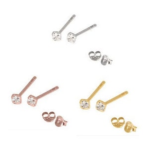 May include: Three pairs of small, square-shaped stud earrings with clear cubic zirconia stones. The earrings are available in silver, rose gold, and gold.