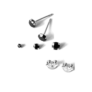 May include: A set of black stud earrings with silver posts. The earrings are of different sizes.