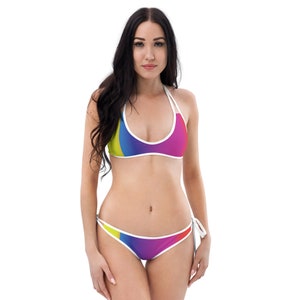 May include: A colorful bikini with a gradient pattern in shades of yellow, blue, purple, and pink. The bikini top has a halter style and the bottom has a tie side.