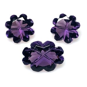 May include: Three purple amethyst gemstones cut in the shape of a four-leaf clover.