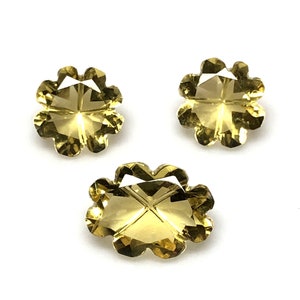 May include: Three yellow topaz gemstones with a flower-shaped cut. The gemstones are faceted and have a clear, bright color.