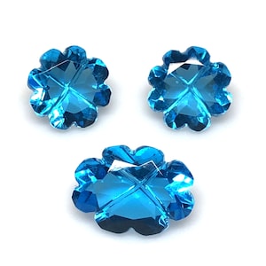 May include: Three blue crystal flower-shaped beads with a cross design in the center.