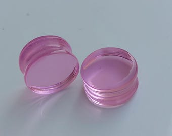 May include: Pair of pink acrylic ear gauges. The gauges are round and have a smooth, glossy finish.
