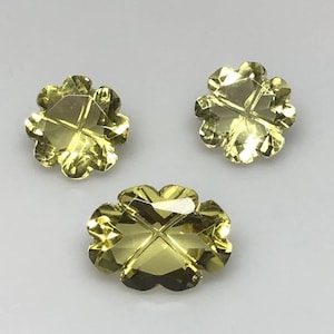 May include: Three yellow-green faceted gemstone clover charms. Each charm has a four-leaf clover shape with a cross in the center.