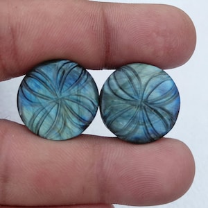 May include: Two round, carved, iridescent blue-green labradorite gemstones with a flower-like design.