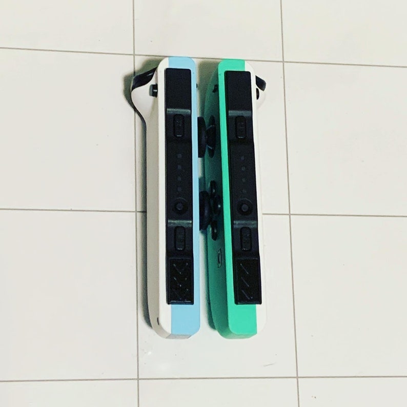 May include: Two Nintendo Switch Joy-Con controllers, one white and blue, the other green. The controllers are side-by-side and have black buttons.