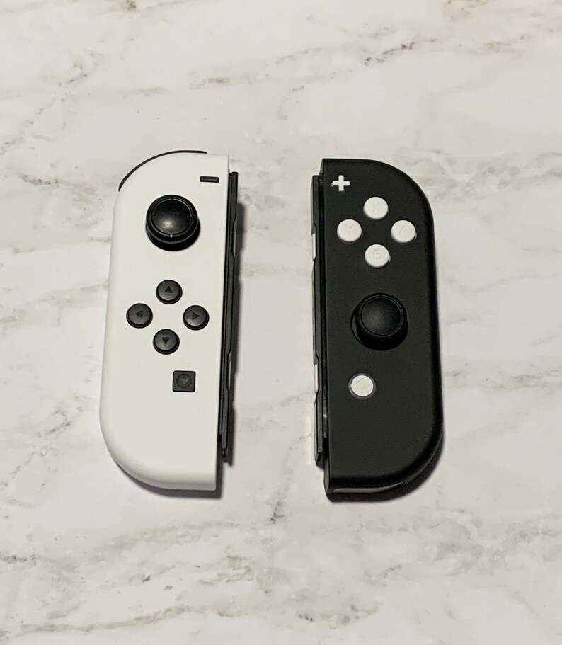 Puede incluir: Dos mandos Joy-Con para Nintendo Switch, uno blanco y otro negro. Ambos mandos tienen los botones y las palancas anal&oacute;gicas est&aacute;ndar.
