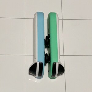 May include: Two Nintendo Switch Joy-Con controllers, one is light blue and white, the other is green and white.