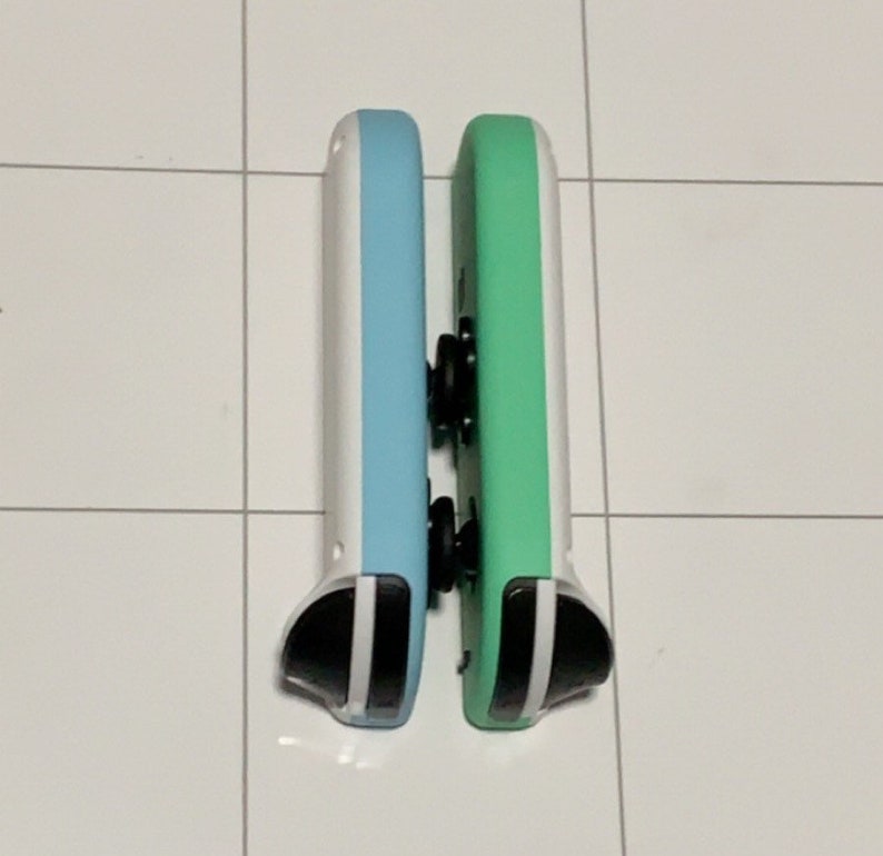 May include: Two Nintendo Switch Joy-Con controllers, one is light blue and white, the other is green and white.