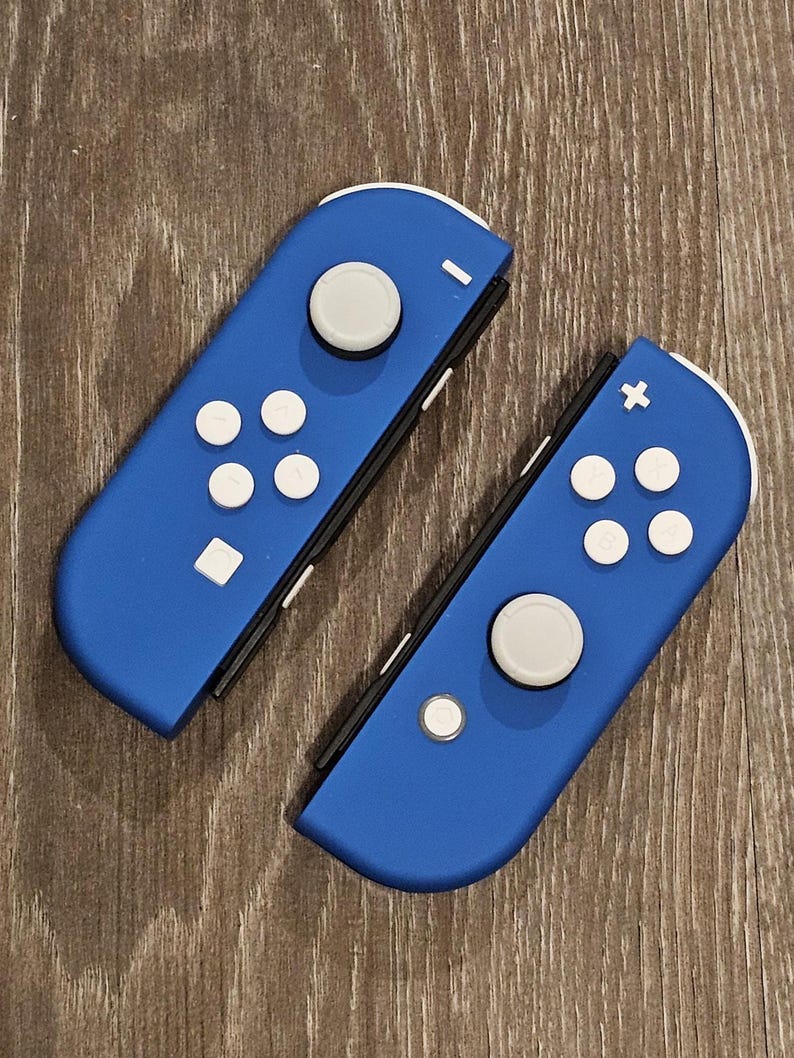 May include: Two blue Nintendo Switch Joy-Con controllers with white buttons. The left Joy-Con has a minus sign and the right Joy-Con has a plus sign.