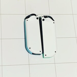May include: Two white Nintendo Switch Joy-Con controllers with black buttons and a blue and green accent on the bottom.