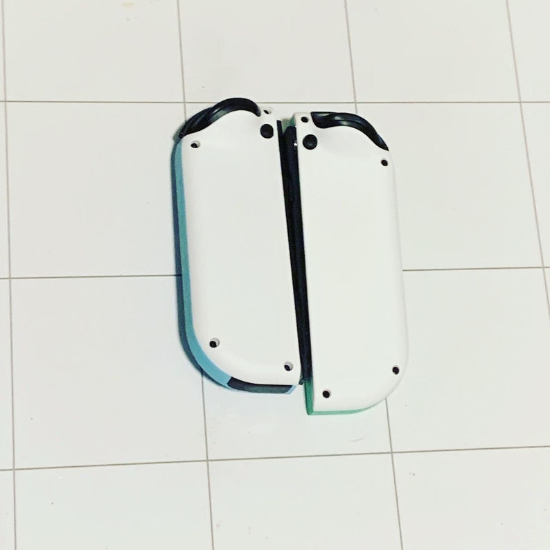 May include: Two white Nintendo Switch Joy-Con controllers with black buttons and a blue and green accent on the bottom.