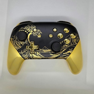 May include: A black and gold Nintendo Switch controller with a wave design. The controller has gold buttons and a gold trim.