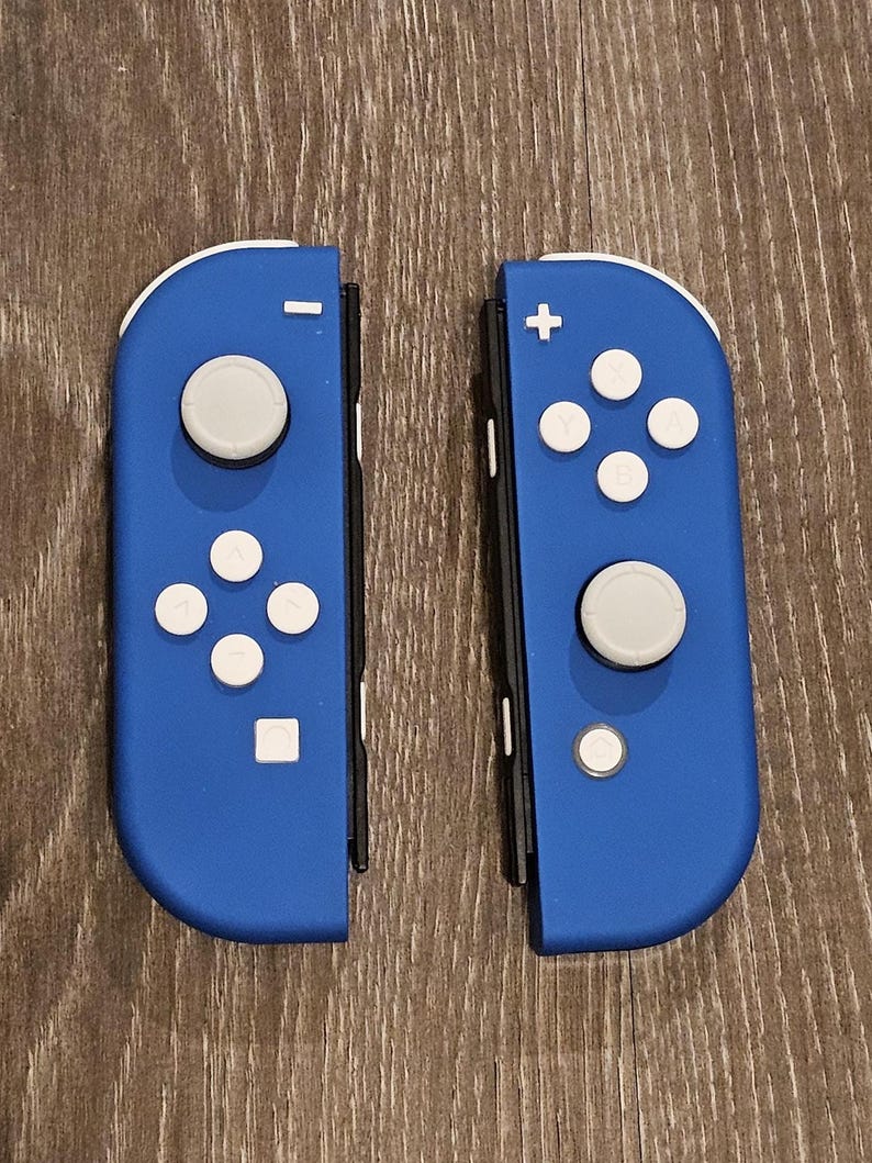May include: A pair of blue Nintendo Switch Joy-Con controllers with white buttons. The controllers are separated and show the front view.
