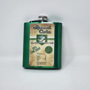 May include: A green metal flask with a silver cap. The flask has a label that says "Speed Cola" and "The Cola that Moves You!" The label also says "100% Cane Sugar" and "10 Cents".