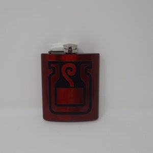 May include: A red metal flask with a black and silver design of a bottle with a swirl on the top.