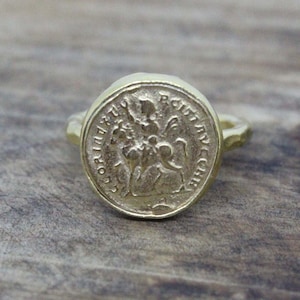 Puede incluir: Un anillo de oro con un diseño redondo en forma de moneda que presenta una imagen en relieve de un caballero a caballo. La moneda tiene la inscripción "S. GIORGIO MARTIRE" alrededor del borde.