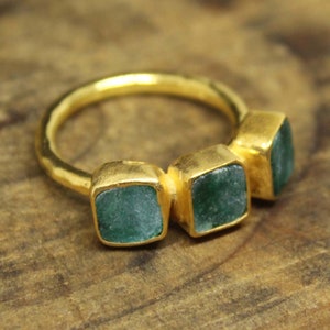 Peut inclure: Bague en or avec trois pierres carrées vert émeraude serties dans la bande.