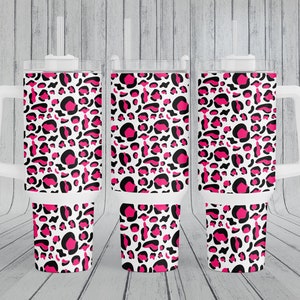 Puede incluir: Tres vasos blancos con un diseño de estampado de leopardo rosa y negro. Los vasos tienen una tapa y un asa.