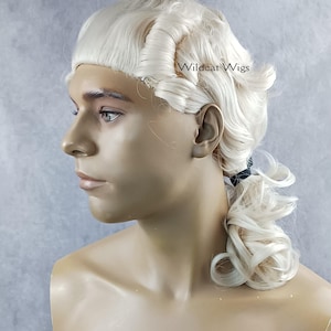 May include: A cream-colored wig with a historical style, featuring tightly curled sections and a low ponytail. The wig is displayed on a mannequin. The text "Wildcat Wigs" is visible on the wig.
