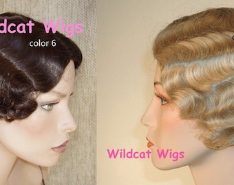 May include: Two vintage style wigs on mannequin heads. The wig on the left is dark brown with finger waves and the text "Wildcat Wigs color 6". The wig on the right is a light blonde with finger waves and the text "Wildcat Wigs color 22".