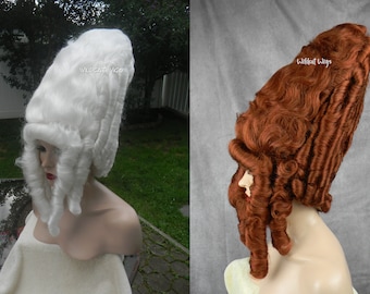 May include: Two large, elaborate wigs on mannequin heads. The wig on the left is white and the wig on the right is a reddish-brown color. Both wigs are styled in a tall, elaborate updo with long, flowing curls.