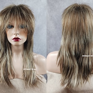 May include: A layered wig with a mullet style, featuring a blend of brown, blonde, and light brown highlights. The wig has a fringe and long, feathered layers. The text "Wildcat Wigs" is visible on the mannequin.