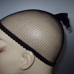 May include: Black mesh wig cap with a lace trim. The cap is designed to fit snugly on the head and is ideal for securing wigs.