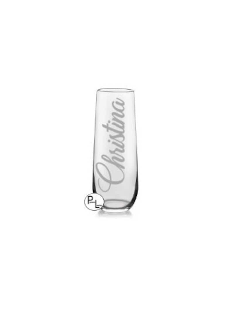 May include: A clear glass champagne flute with the name "Christina" etched on the side.