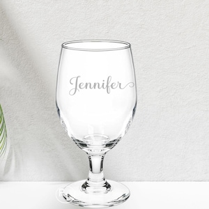 May include: A clear glass wine glass with a stem and a wide bowl. The glass is engraved with the name "Jennifer".