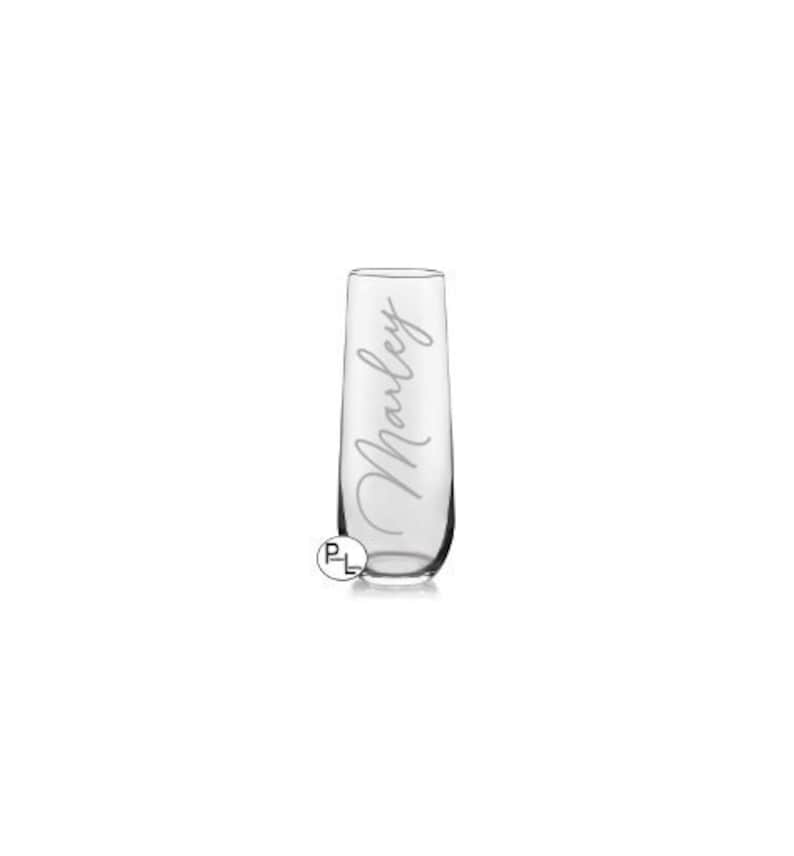 May include: A clear glass champagne flute with the name "Marley" etched on the side.