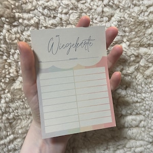 Puede incluir: Una tarjeta blanca con el texto "Wiegekarte" escrito en cursiva negra. La tarjeta tiene un borde de color arcoíris y está dividida en dos columnas con líneas para escribir.