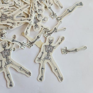 May include: A pile of white skeleton cutouts, perfect for Halloween crafts or decorations. The skeletons are in various poses, with some arms and legs detached.