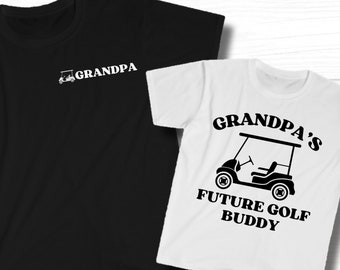 Puede incluir: Dos camisetas blancas y negras. La camiseta más grande tiene el texto "GRANDPA" con un icono de carrito de golf. La camiseta más pequeña tiene el texto "GRANDPA'S FUTURE GOLF BUDDY" con un icono de carrito de golf.