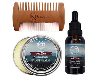 May include: A wooden dual-sided beard comb with the KT Valley Co. logo, a round metal tin of Cherry Tobacco beard balm labeled 2 oz | 57 g, and a dark glass dropper bottle of Cherry Tobacco beard oil labeled 1 fl oz | 30 ml.