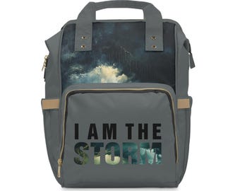 May include: Gray canvas backpack with a storm cloud design and the text "I AM THE STORM" printed on the front.