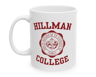 Op de afbeelding: Een witte keramische mok met een rood logo met de tekst "HILLMAN COLLEGE" en een rood zegel met de tekst "DEUS NONDU TE CONFECTI *1881*"