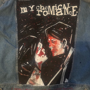 May include: A light blue denim jacket with a painted design on the back. The design features the words "My Chemical Romance" in white, with an illustration of two figures. Red text at the top and bottom of the jacket.