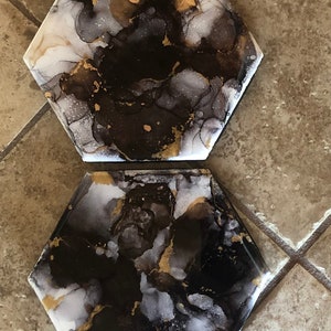 Abstract black and gold faux marble pattern, painted with alcohol inks on a ceramic hexagon tile coaster,