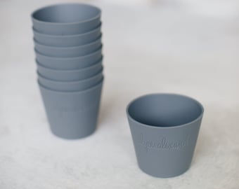 Peut inclure: Une pile de dix gobelets en silicone gris avec les mots "lycee alexandre" gravés sur le gobelet du bas.