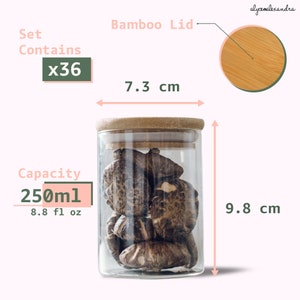 Może przedstawiać: Zestaw 36 przezroczystych szklanych słoik&oacute;w z bambusowymi pokrywkami. Każdy słoik ma pojemność 250 ml (8,8 fl oz) i mierzy 9,8 cm wysokości i 7,3 cm średnicy.