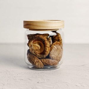 May include: A glass jar with a wooden lid filled with dried shiitake mushrooms.