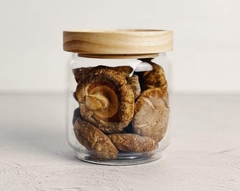 Peut inclure: Un bocal en verre avec un couvercle en bois rempli de champignons shiitaké séchés.