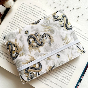 May include: A white book cover featuring a black and gold dragon design. The cover has a white elastic band to hold it closed. The text "FOR TRUE LOVE" is printed on the cover.