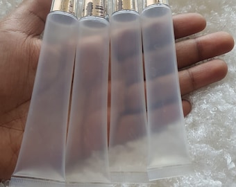 May include: Four clear plastic tubes with silver caps. The tubes are empty and are held in a hand.