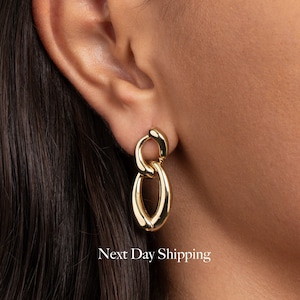 Puede incluir: Pendientes de cadena de eslabones dorados con un diseño grueso y ovalado.