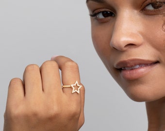 May include: A gold ring with a star-shaped design set with clear stones.