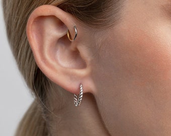 May include: Silver twisted hoop earrings. The earrings are small and delicate, and they are perfect for everyday wear.